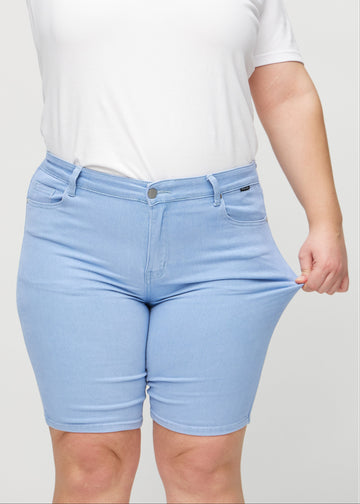 Plus-size-modellen drar ut shortsen vid låret för att visa stretch.