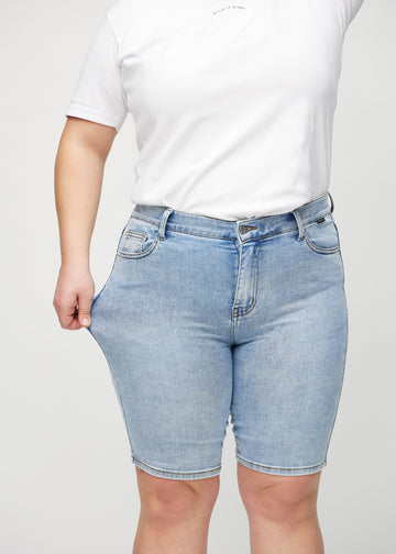 Plus-size-modellen drar ut shortsen vid låret för att visa stretch.