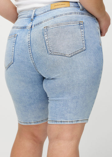 Ljus denim skinny middle shorts sedda bakifrån i närbild på en plus-size-modell för att visa detaljer.