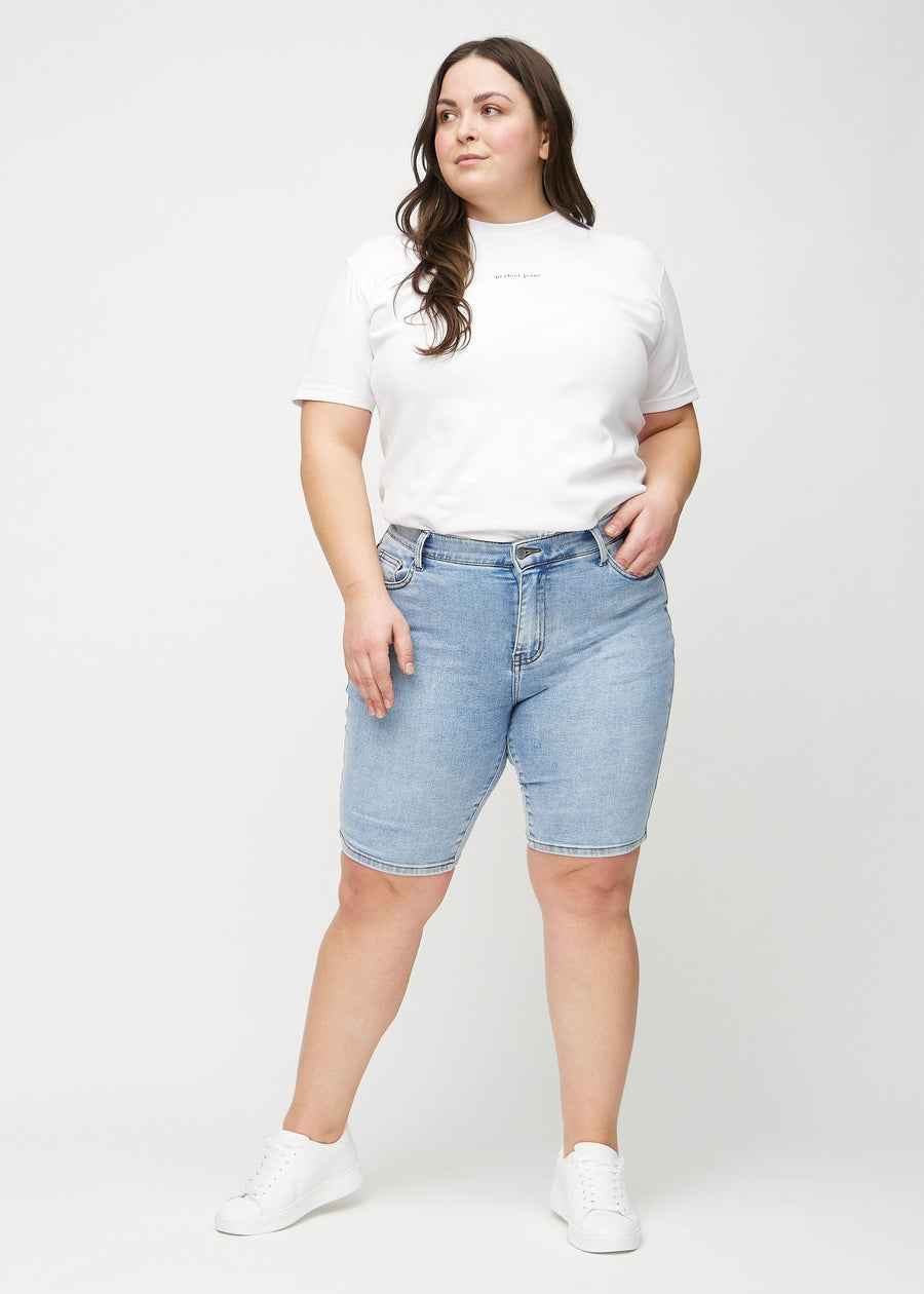 Helbild av en plus-size-modell i ljus denim skinny middle shorts.