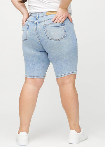 Ljus denim skinny middle shorts sedda bakifrån på en plus-size-modell, så att man kan se hela produkten.