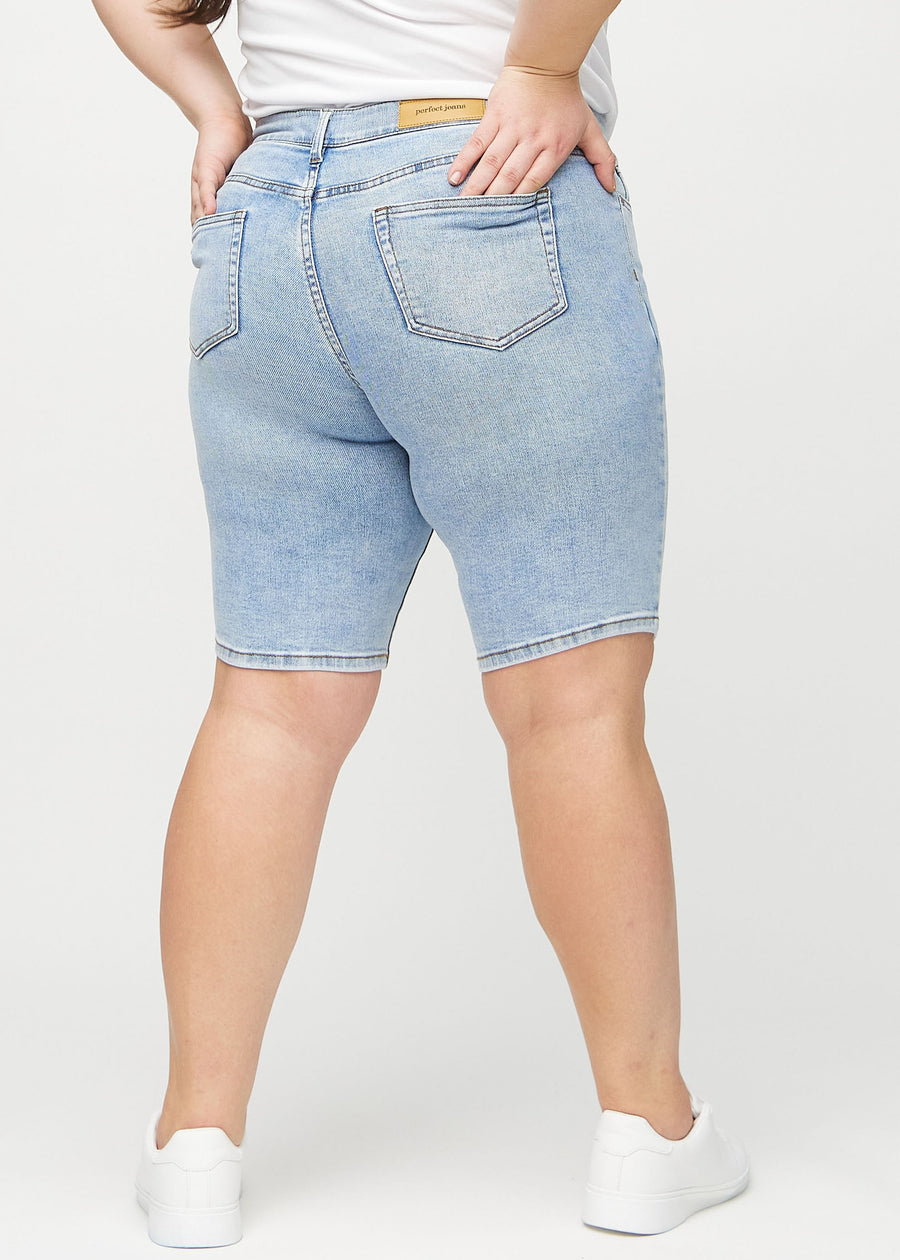 Ljus denim skinny middle shorts sedda bakifrån på en plus-size-modell, så att man kan se hela produkten.