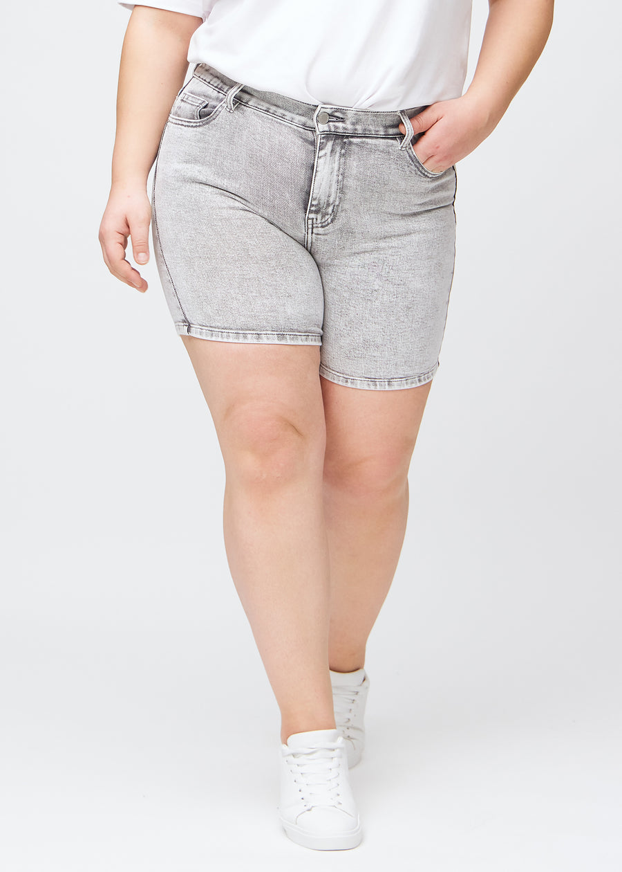 Ljusgrå denim skinny short shorts, modellnamn Ashes, som sitter tätt och slutar mitt på låret på en plus size-modell, sedd framifrån.