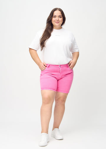 Helbild av en plus-size-modell i ljusrosa skinny short shorts.