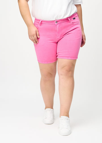 Ljusrosa skinny short shorts, modellnamn Flamingos, som sitter tajt och slutar mitt på låret på en plus-size-modell, sett framifrån.