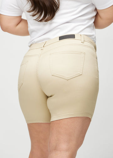 Beige skinny short shorts sedda bakifrån i närbild på en plus-size-modell för att visa detaljer.