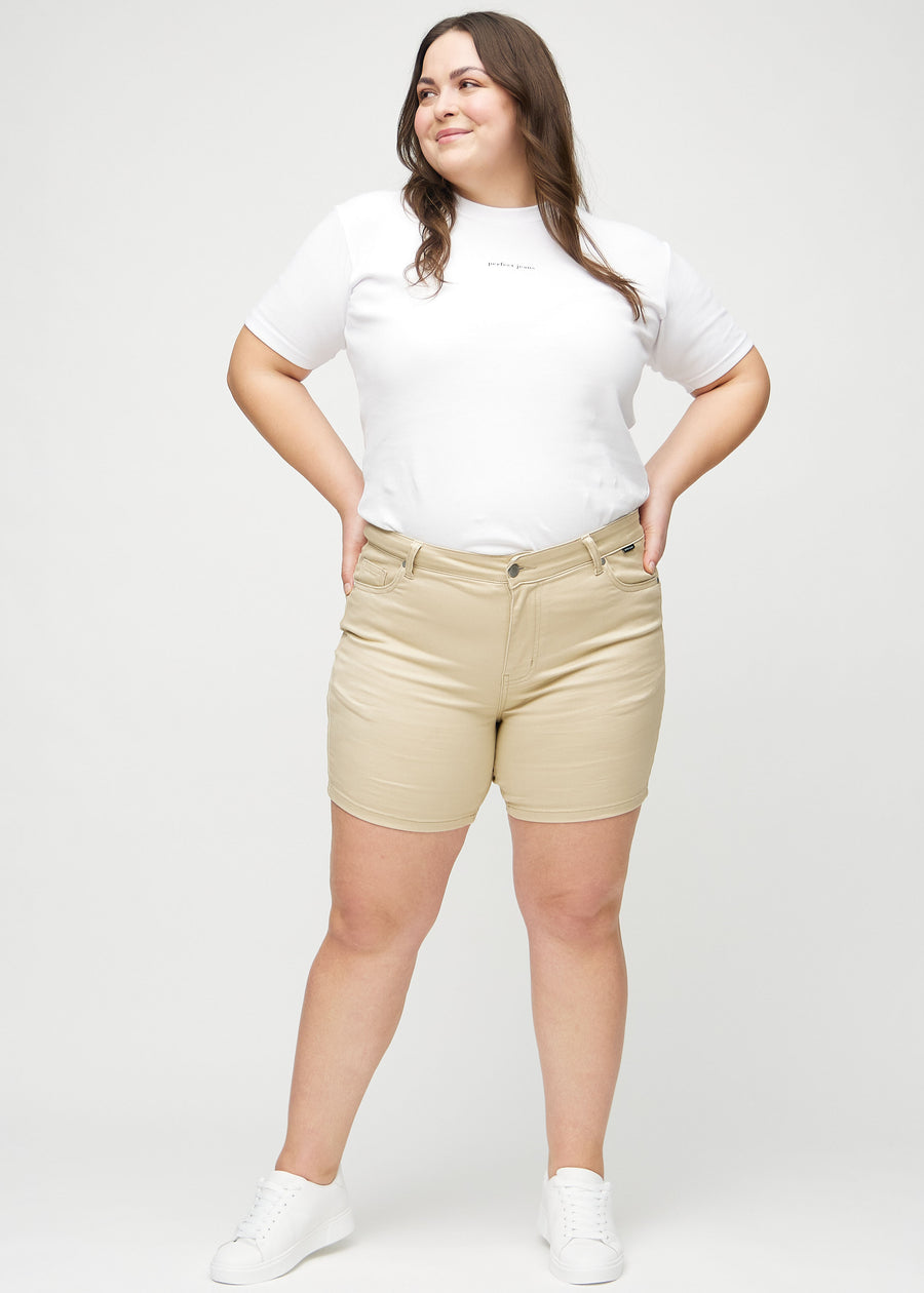 Helbild av en plus-size-modell i beige skinny short shorts.