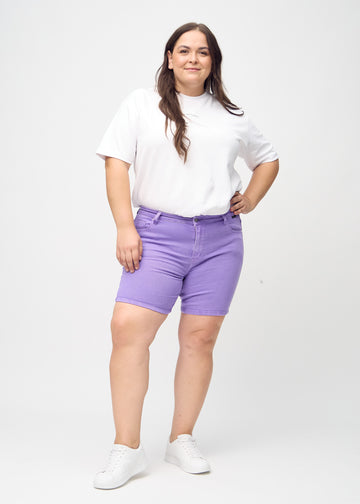 Helbild av en plus-size-modell i lila skinny short shorts.