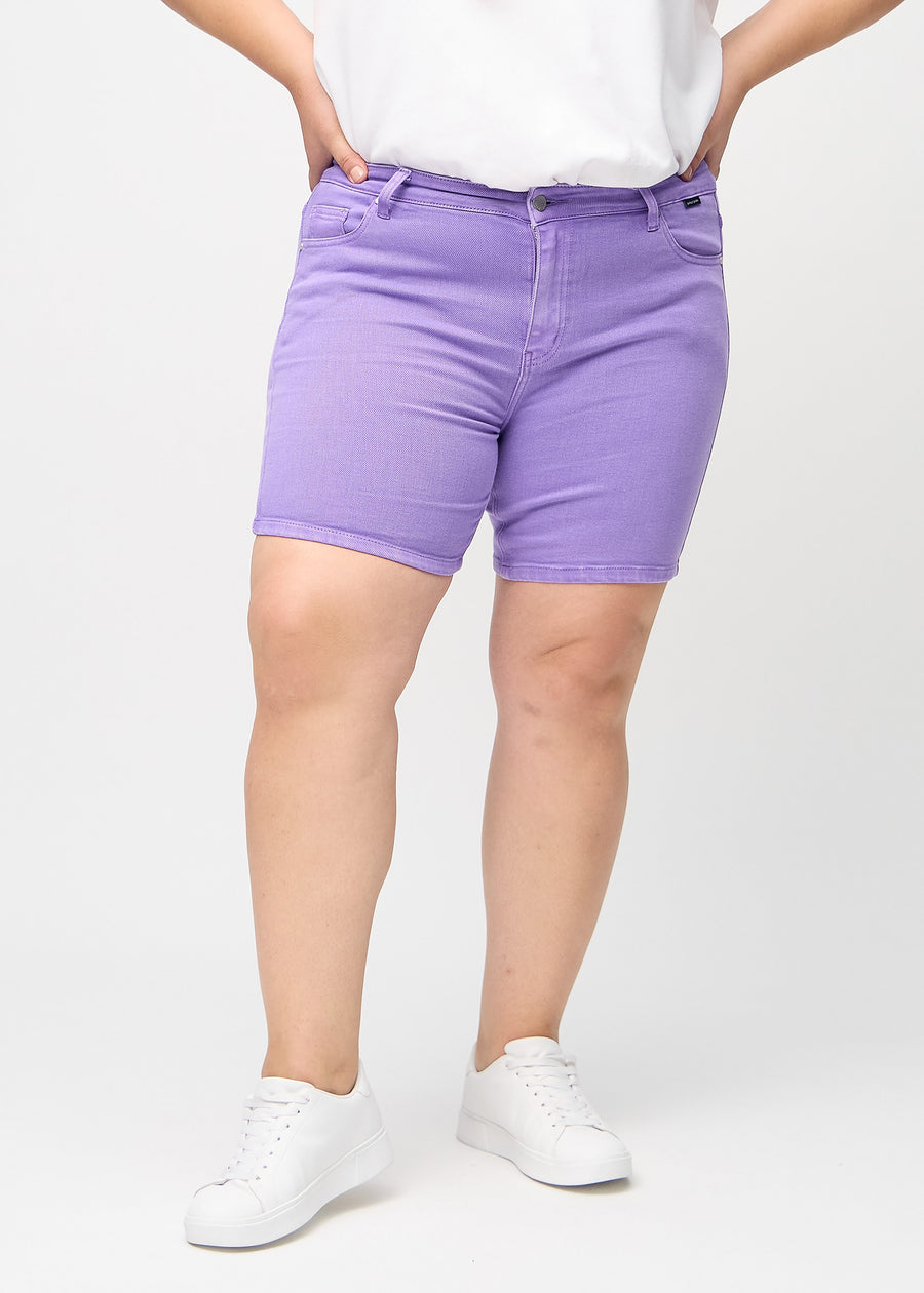 Lila skinny short shorts, modellnamn Lavenders, som sitter tight och slutar mitt på låret på en plus-size-modell, sett framifrån.