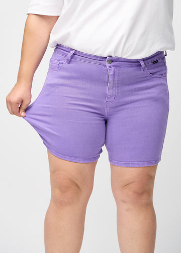 Plus-size-modellen sträcker ut shortsen vid låret för att visa stretchen.