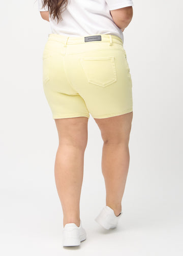 Ljusgula skinny short shorts sedda bakifrån på en plus-size-modell, så att man kan se hela produkten.