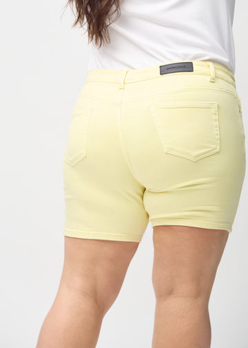Ljusgula skinny short shorts sedda bakifrån i närbild på en plus-size-modell för att visa detaljer.