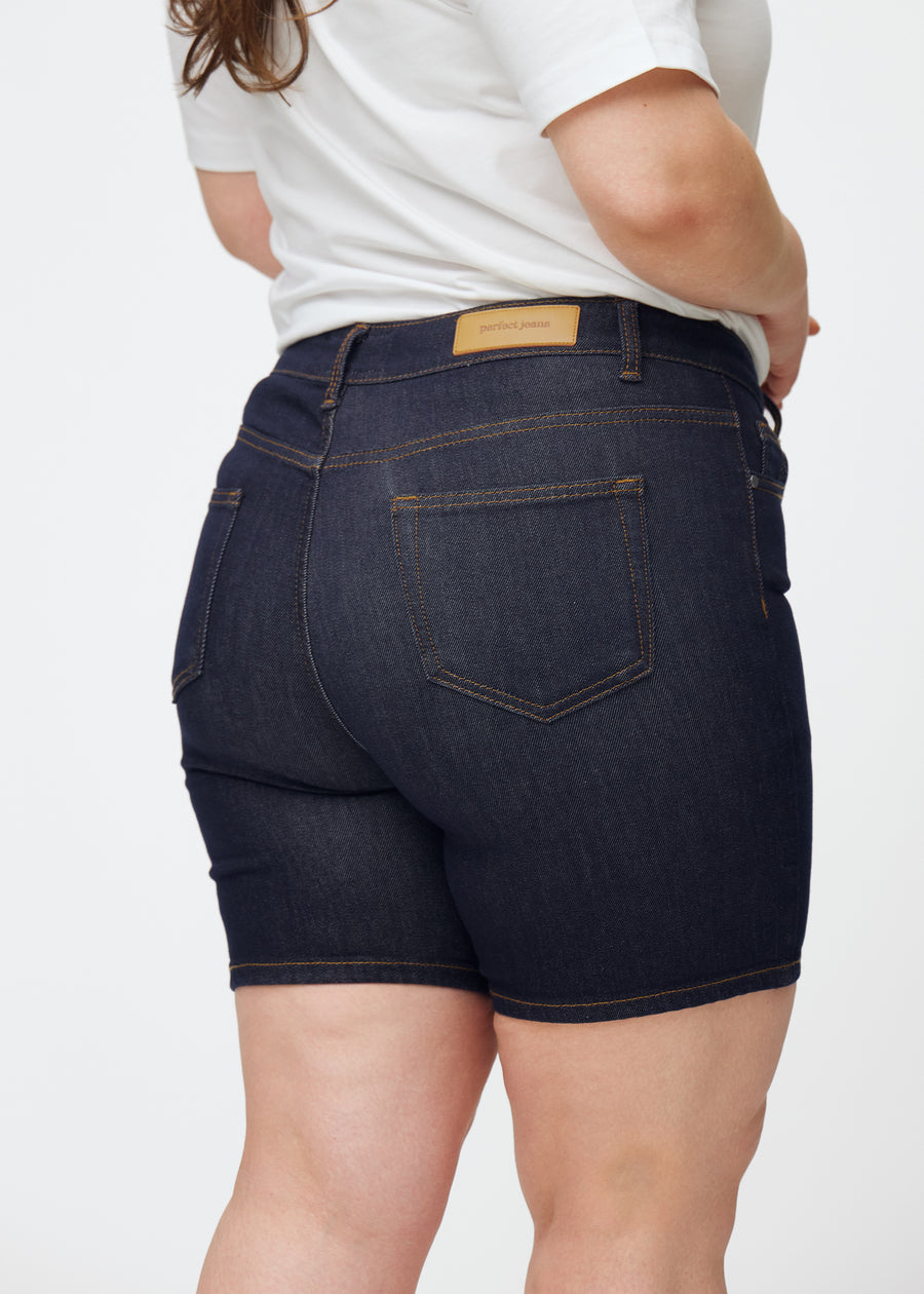 Mörkblå denimshorts för dam i färgen Midnights sett bakifrån i närbild på plus-size modell för att visa passform och detaljer.