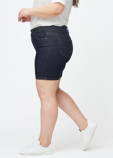 Mörkblå denimshorts för dam i färgen Midnights med skinny passform sett från sidan på plus-size modell.