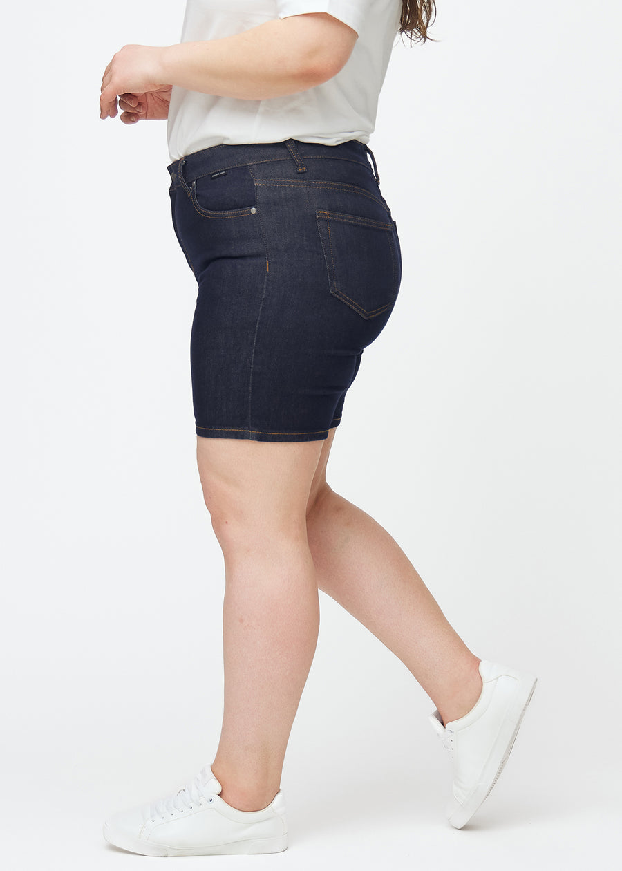 Mörkblå denimshorts för dam i färgen Midnights med skinny passform sett från sidan på plus-size modell.