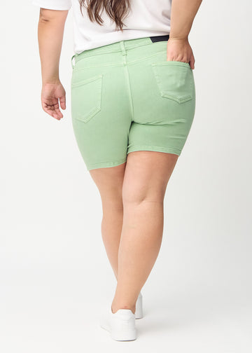 Ljusgröna skinny short shorts sedda bakifrån på en plus-size-modell, så att man kan se hela produkten.