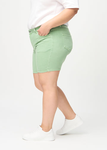 Ljusgröna skinny short shorts sedda från sidan på en plus-size-modell.