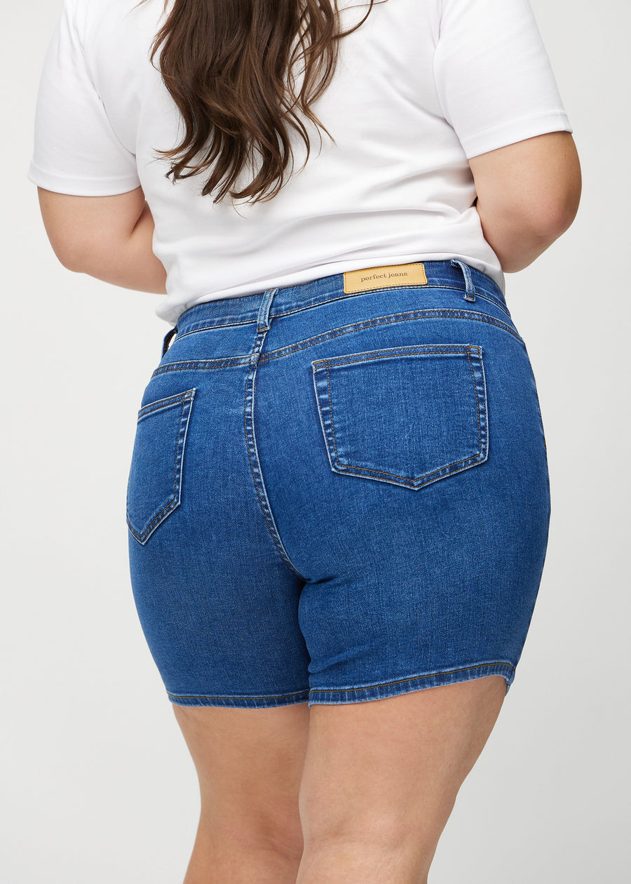 Mörk denim skinny short shorts sedda bakifrån i närbild på en plus-size-modell för att visa detaljer.
