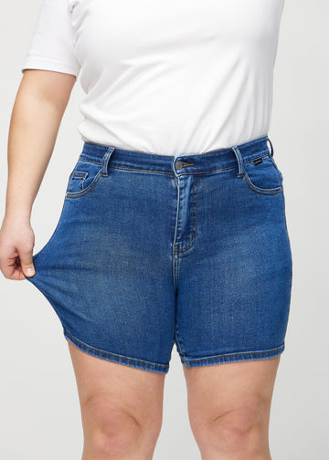 Plus-size-modellen drar ut shortsen vid låret för att visa stretch.