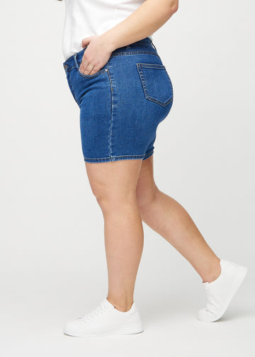 Mörk denim skinny short shorts sedda från sidan på en plus-size-modell.