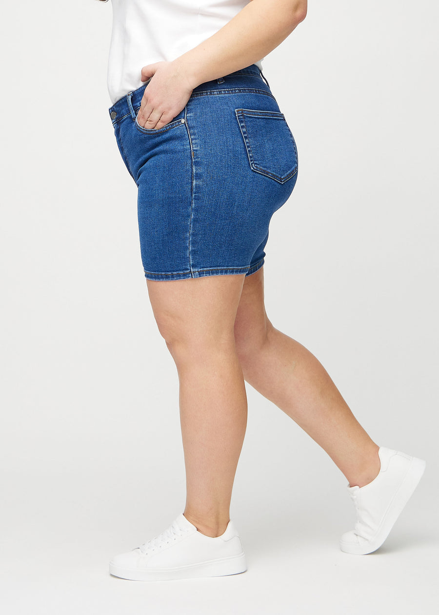 Mörk denim skinny short shorts sedda från sidan på en plus-size-modell.