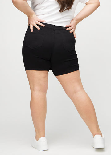 Svarta skinny short shorts sedda bakifrån på en plus size-modell, så att hela produkten syns.
