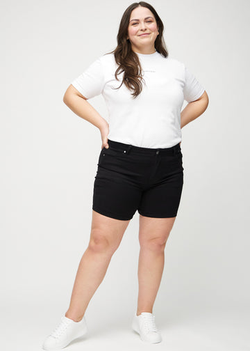 Helbild av en plus size-modell i svarta skinny short shorts.