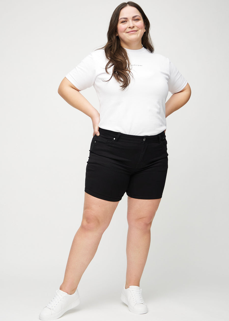 Helbild av en plus size-modell i svarta skinny short shorts.