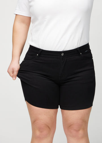 Plus size-modellen drar ut shortsen vid låret för att visa stretch.