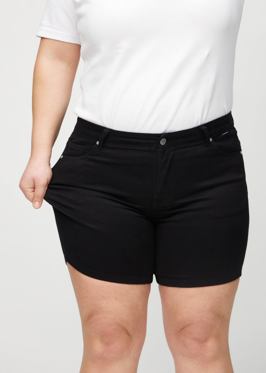 Plus size-modellen drar ut shortsen vid låret för att visa stretch.