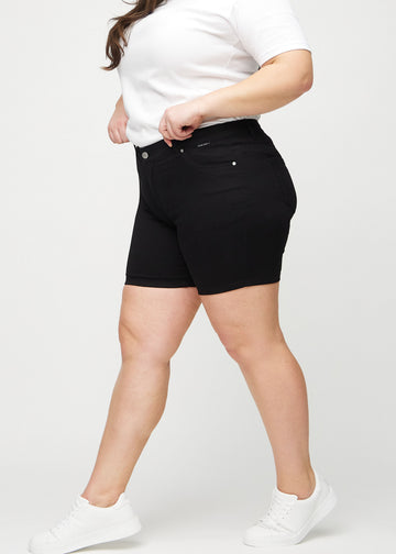 Svarta skinny short shorts sedda från sidan på en plus size-modell.