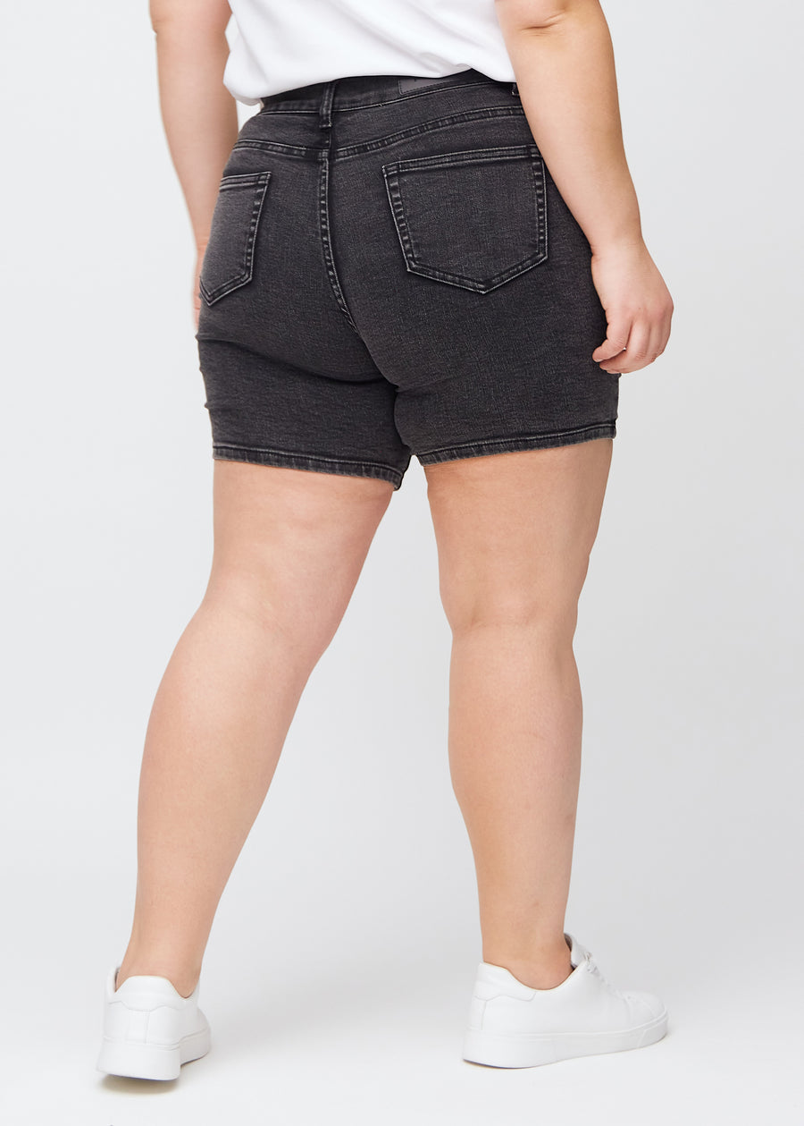 Mörkgrå denim skinny short shorts sedda bakifrån på en plus size-modell, så att man kan se hela produkten.