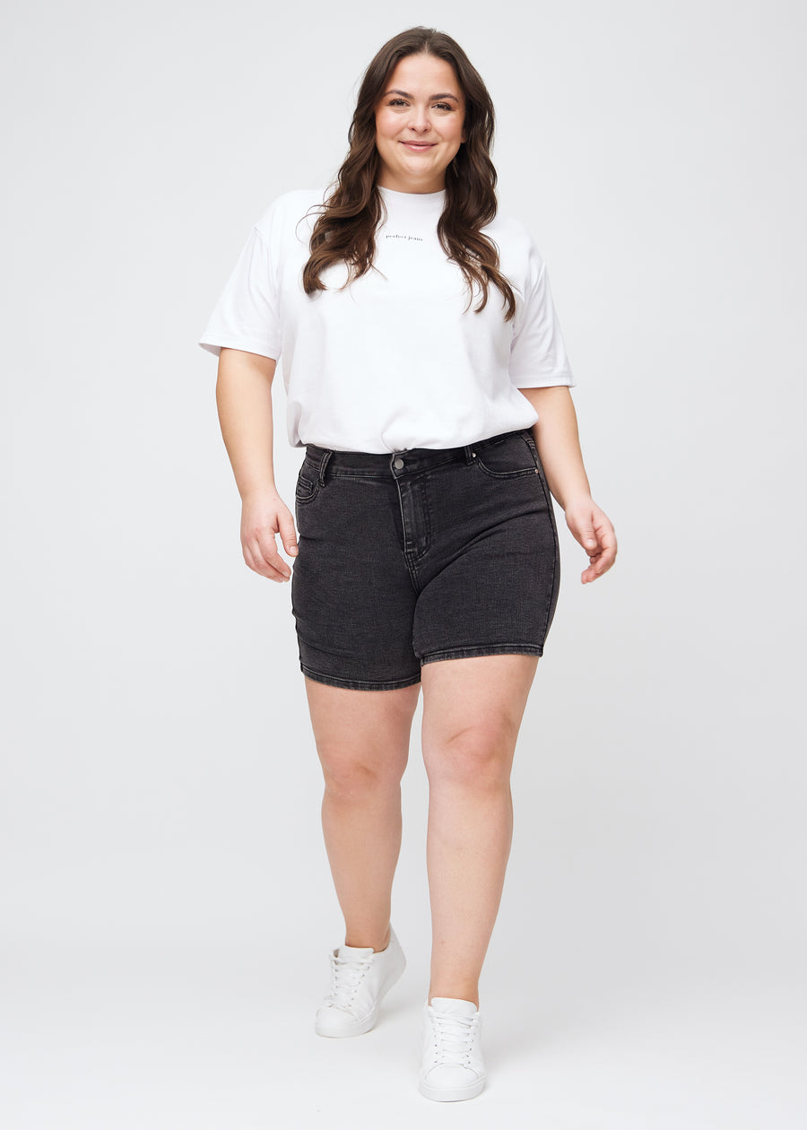 Helbild av en plus size-modell i mörkgrå denim skinny short shorts.