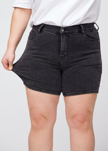Plus size-modellen drar ut shortsen vid låret för att visa stretch.