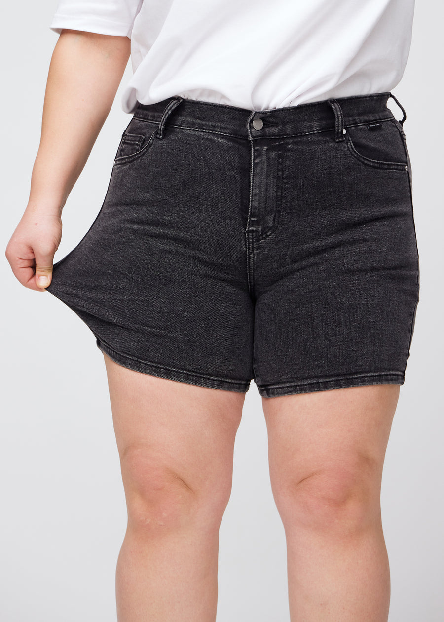 Plus size-modellen drar ut shortsen vid låret för att visa stretch.