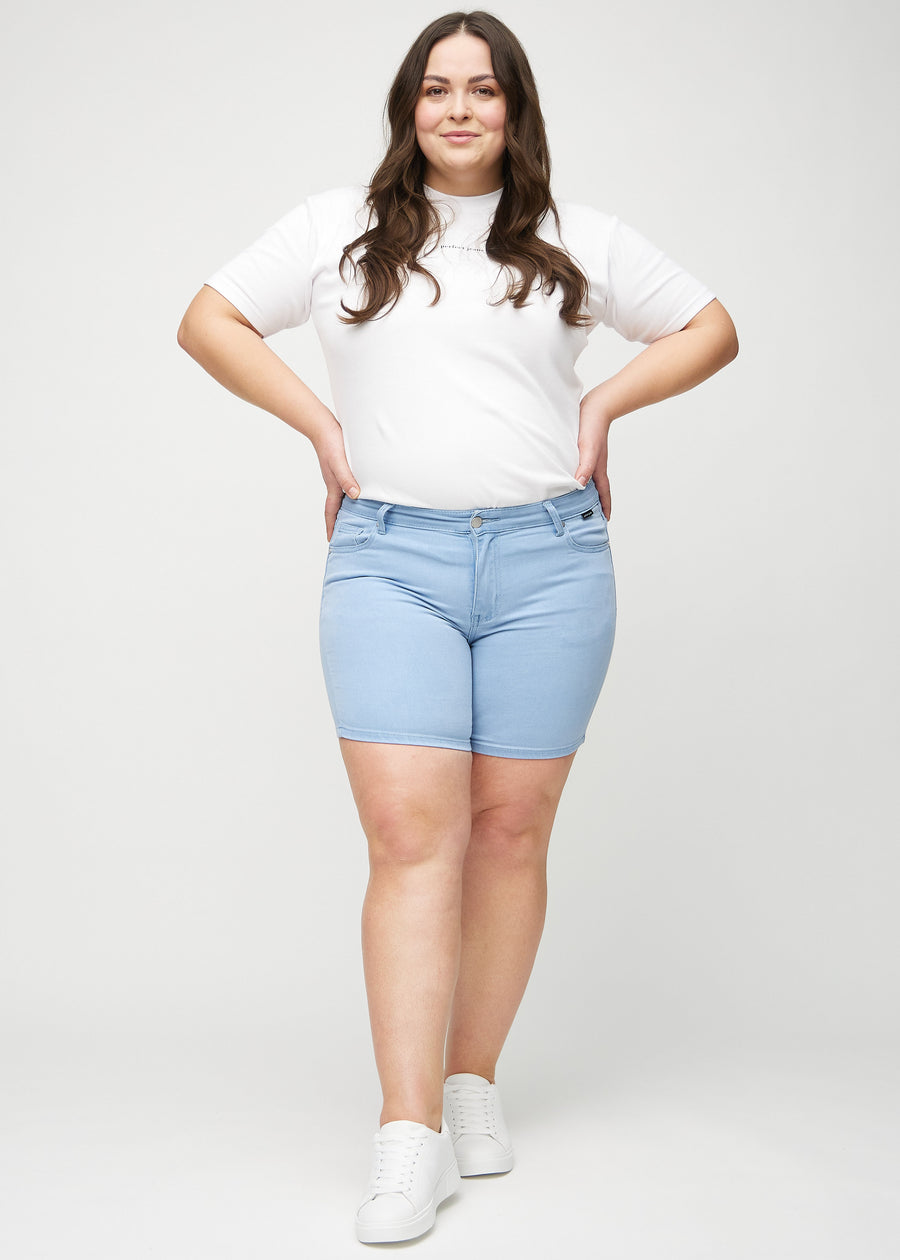 Helbild av en plus size-modell i ljusblå skinny short shorts.