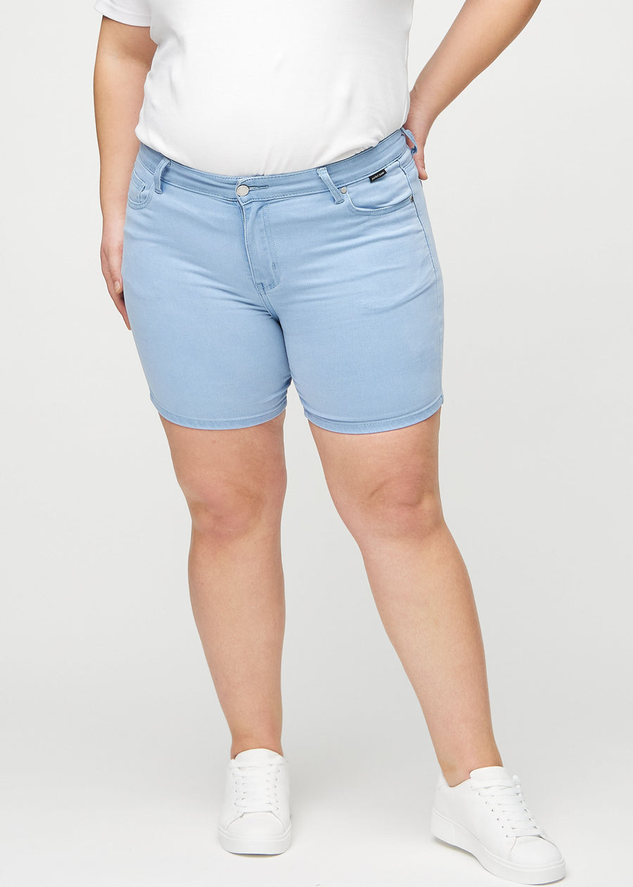 Ljusblå skinny short shorts, modellnamn Skies, som sitter tight och slutar mitt på låret på en plus size-modell, sett framifrån.