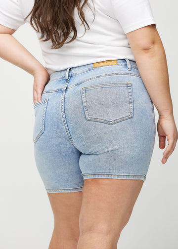 Ljus denim skinny short shorts sedda bakifrån i närbild på en plus size-modell för att visa detaljer.