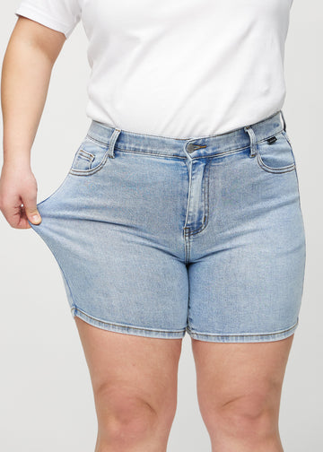 Plus size-modellen drar ut shortsen vid låret för att visa stretchen.