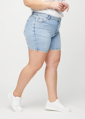 Ljus denim skinny short shorts sedda från sidan på en plus size-modell.
