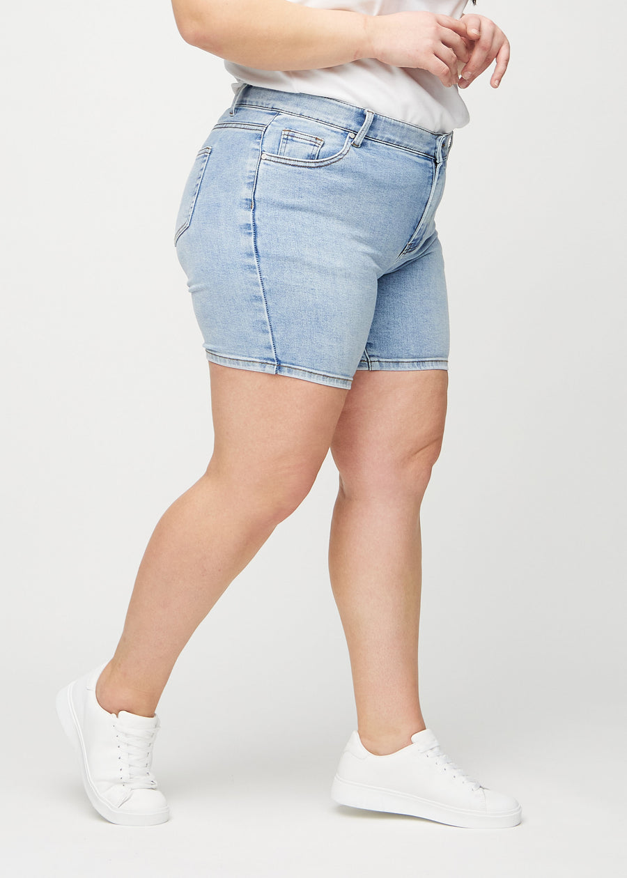 Ljus denim skinny short shorts sedda från sidan på en plus size-modell.