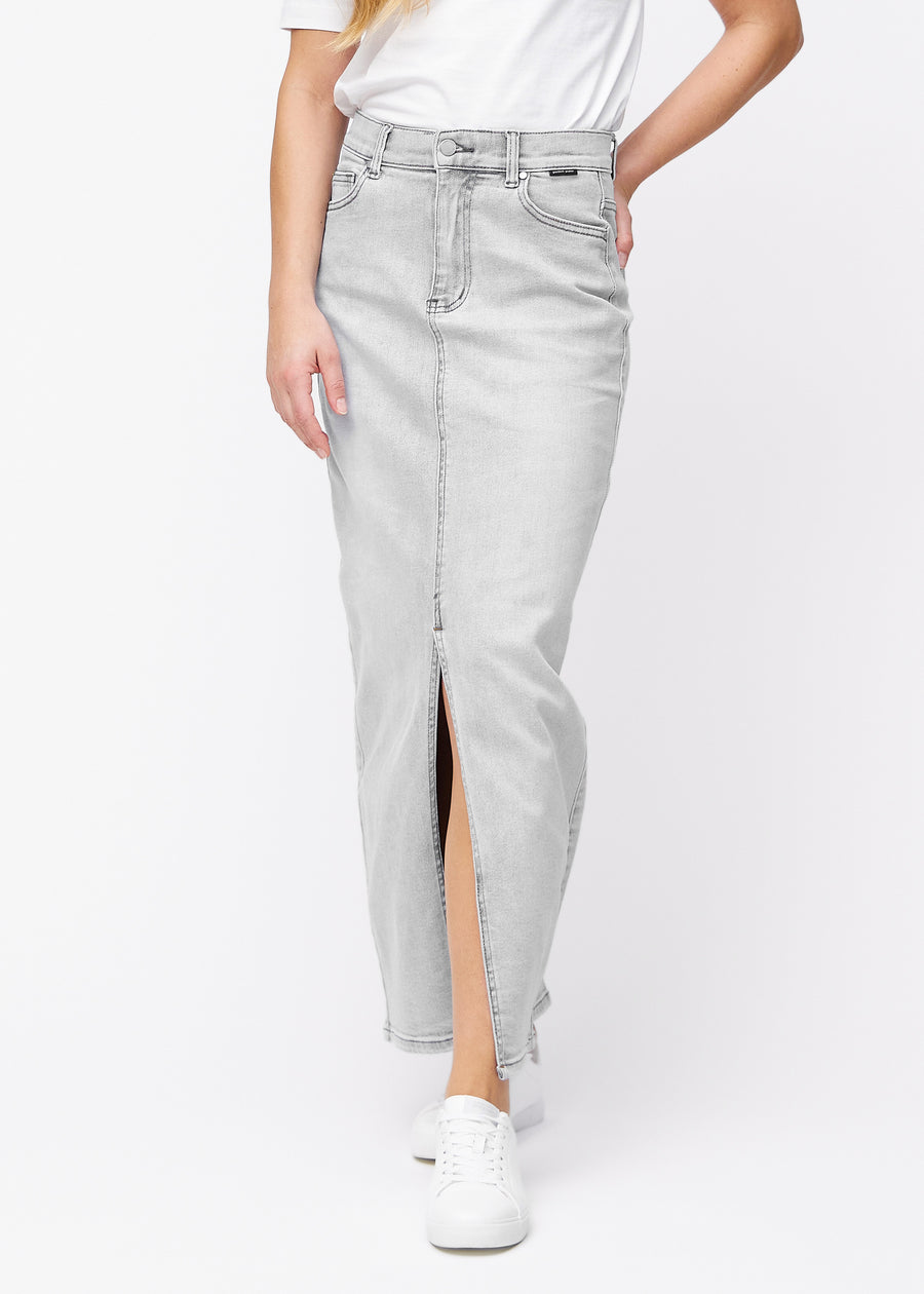 Lång ljusgrå denimkjol för kvinnor i färgen Ashes. Framifrån på en modell, med rakt fall från höfterna och en slits framtill som börjar strax under knät.