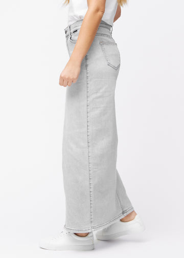 Lång ljusgrå denimkjol för kvinnor i färgen Ashes. Från sidan på en modell, med synlig slits framtill.