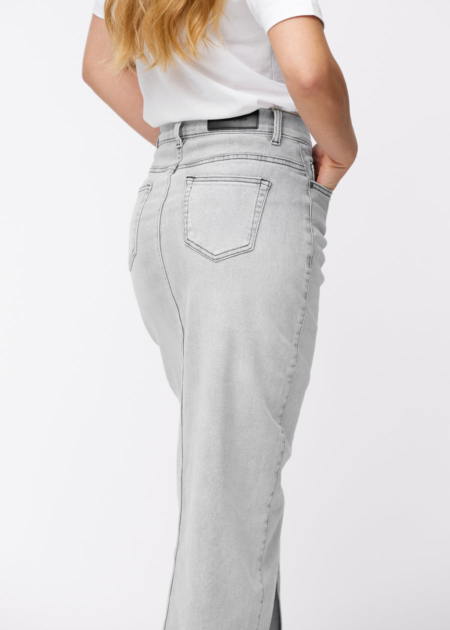 Lång ljusgrå denimkjol för kvinnor i färgen Ashes. Närbild bakifrån på en modell som visar passform och detaljer.