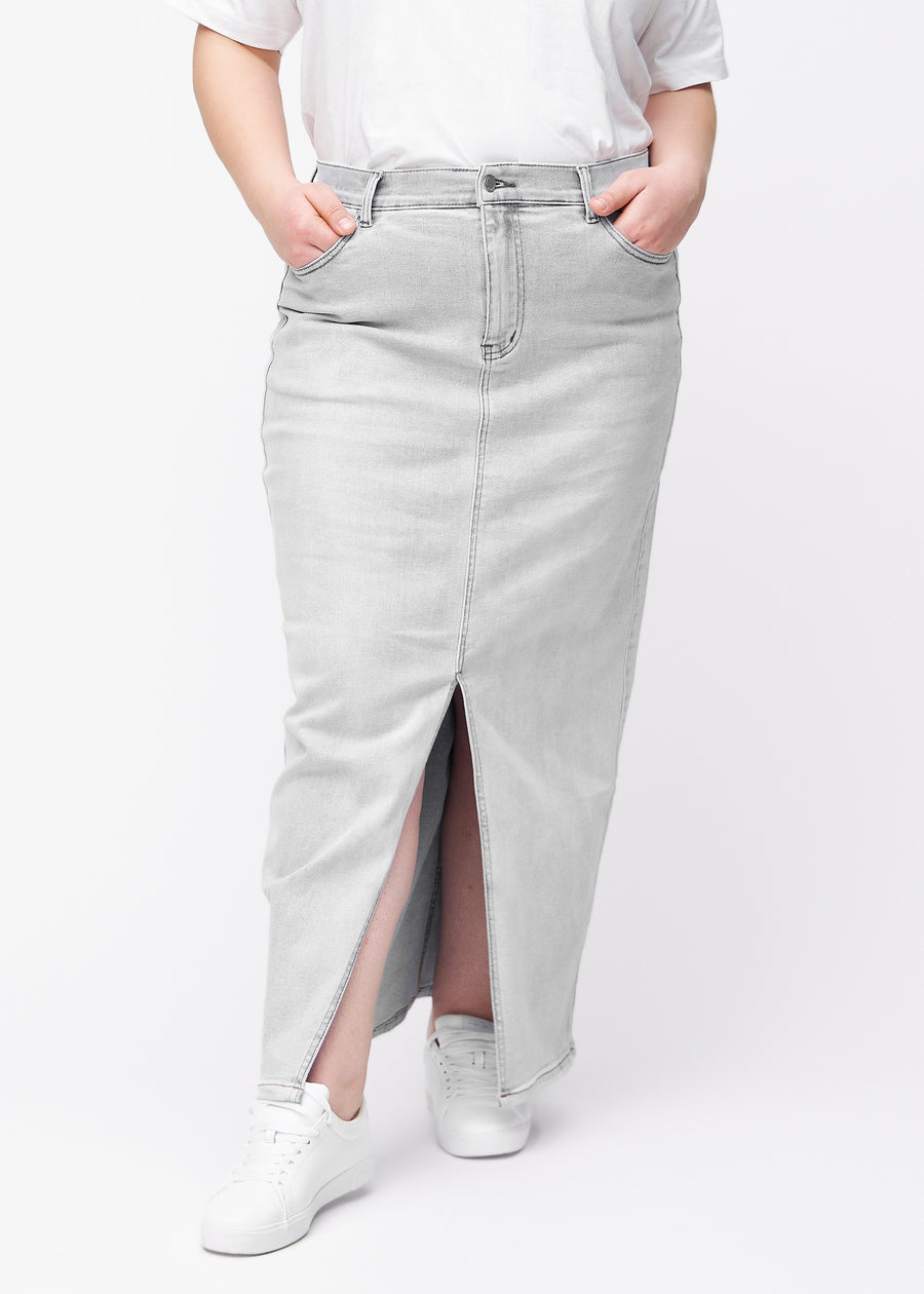 Lång ljusgrå denimkjol för kvinnor i färgen Ashes. Framifrån på en plus size-modell, med rakt fall från höfterna och en slits framtill som börjar strax under knät.