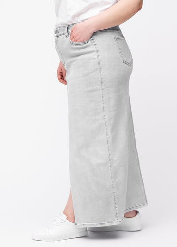 Lång ljusgrå denimkjol för kvinnor i färgen Ashes. Från sidan på en plus size-modell, med synlig slits framtill.