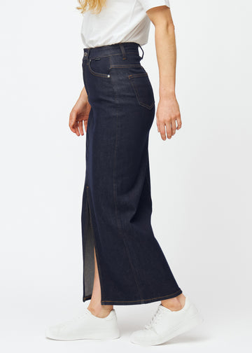 Lång mörkblå denimkjol för dam i färgen Midnights sett från sidan på modell, med synlig slits framtill.