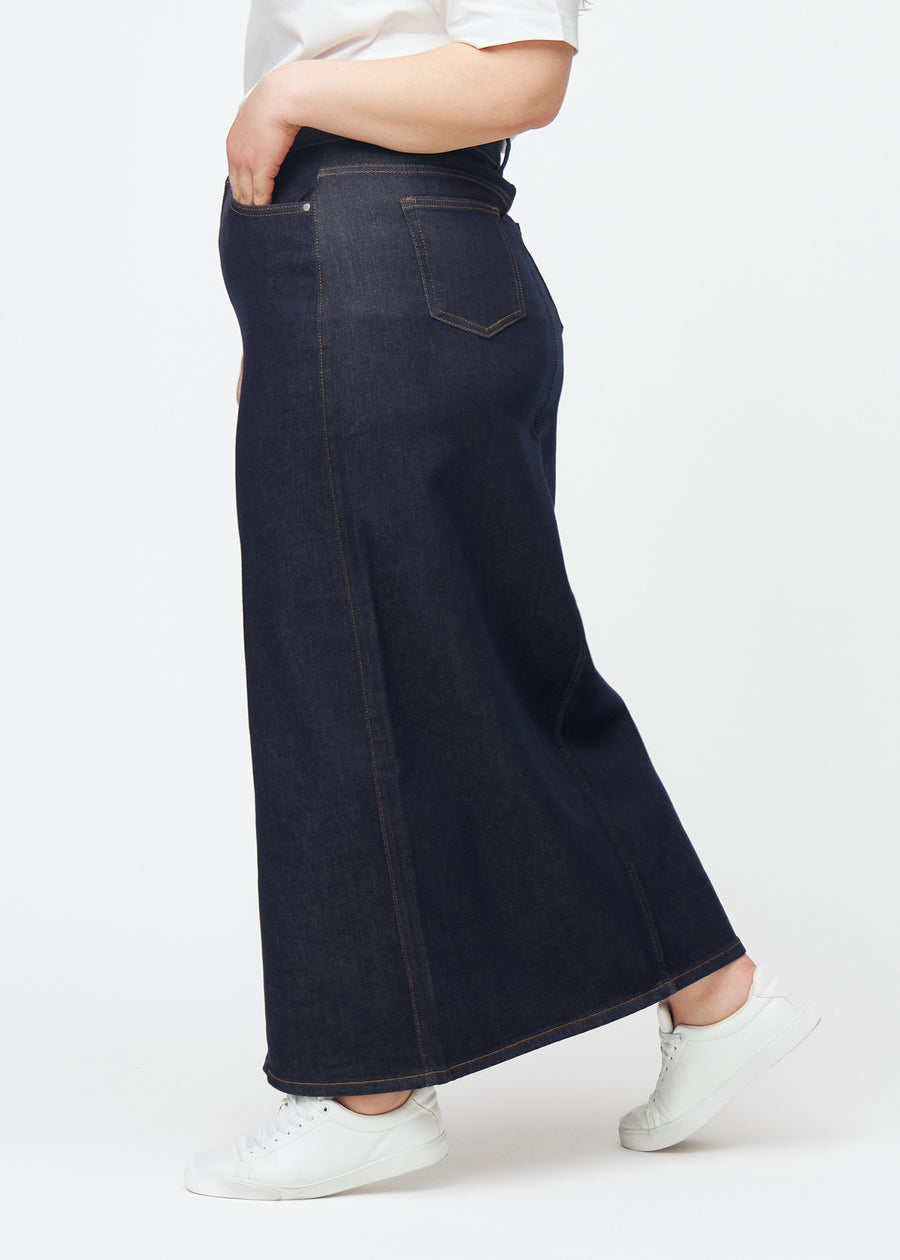 Lång mörkblå denimkjol för dam i färgen Midnights sett från sidan på plus-size modell, med synlig slits framtill.