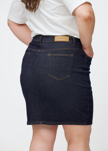 Mörkblå denimkjol för dam i färgen Midnights sett bakifrån i närbild på plus-size modell.