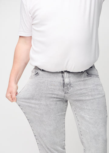 Plus size-modellen sträcker ut jeansen vid låret för att visa stretch.